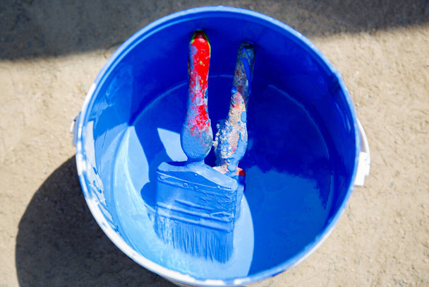 Detailní záběr na kbelík s modrou barvou a štětci.Selektivní zaměření - Fotografie, Obrázek