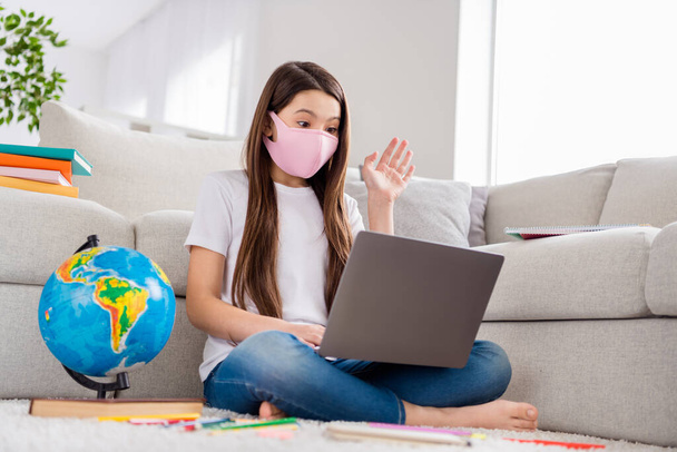 Photo of small pupil school girl notebook laptop raise arm know question answer teacher online lesson geography object sit floor domestic distance quarantine study safety face mask indoors - 写真・画像