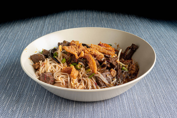 nouilles birmanes avec viande, foie, porc frit, tomate, champignons, chili et autres légumes servis dans une assiette
 - Photo, image