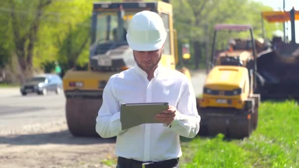 Worker with personal tablet on road works. Manager of the repair works on road, inputs data in his computer - Imágenes, Vídeo