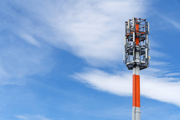 Red and white transmission mast against the blue sky with white clouds  - Photo, Image