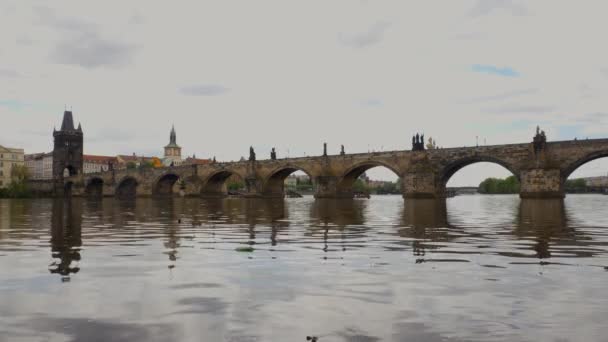 プラハのカレル橋と背景のヴルタヴァ川は古い建築物で見ることができます。 - 映像、動画