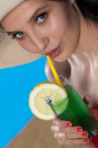 Młoda dziewczyna spogląda w obiektyw i trzyma zimny napój alkoholowy w ręce. - Zdjęcie, obraz