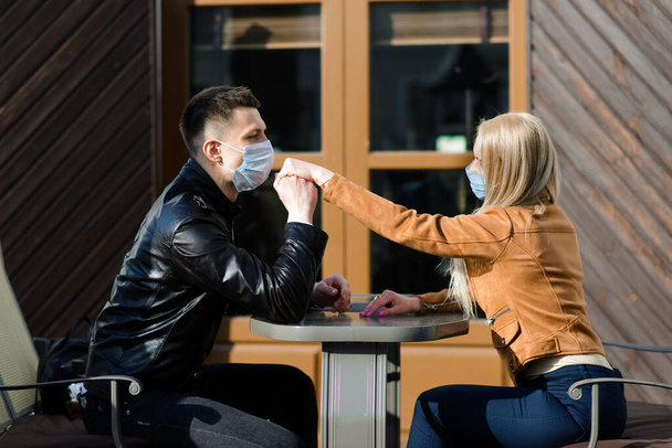 路上で顔の屋外で保護医療マスクの愛の若いカップル。ウイルス対策の男と女. - 写真・画像
