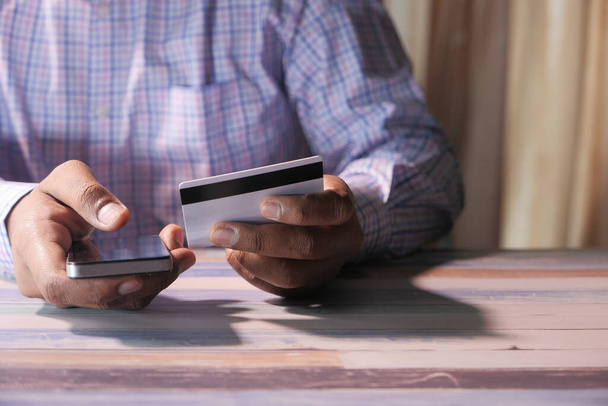 Muž držící kreditní kartu a pomocí chytrého telefonu, koncept nakupování online - Fotografie, Obrázek
