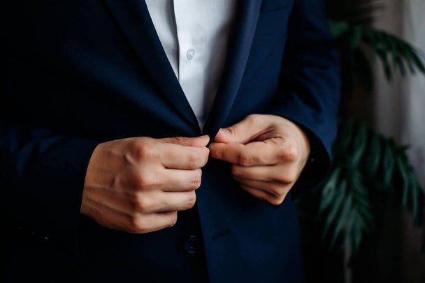 A man in a blue suit zips up his jacket, close-up. Businessman changing clothes.Tonal correction. FASHION, STYLE. close up - Fotó, kép