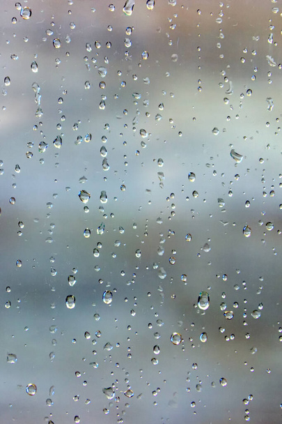 raindrops on a glass window with blurry cloudy sky background - Foto, Imagen
