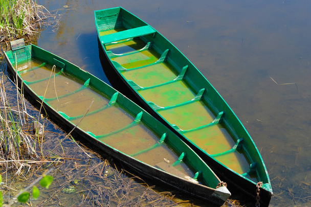 Zwei alte Fischerboote, die ans Ufer geworfen wurden. Abgenutzte und verblichene Holzboote im gelben Gras am Seeufer. Nizza - Foto, Bild