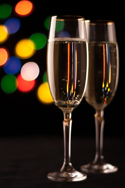 two glasses of champagne toasting against bokeh lights background - Фото, зображення
