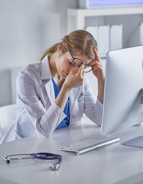 Young female doctor tired after working with computer - Φωτογραφία, εικόνα
