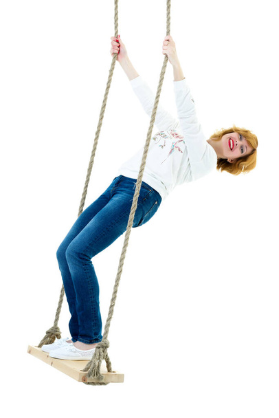 beautiful young woman on a swing against white studio. - 写真・画像