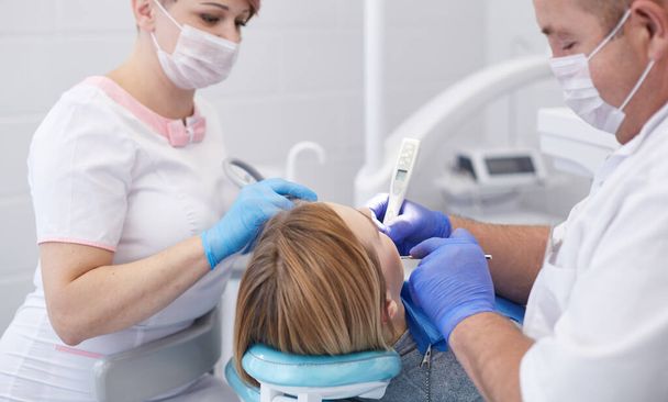 Doctor dentist treats teeth of a beautiful young girl patient. - Fotoğraf, Görsel