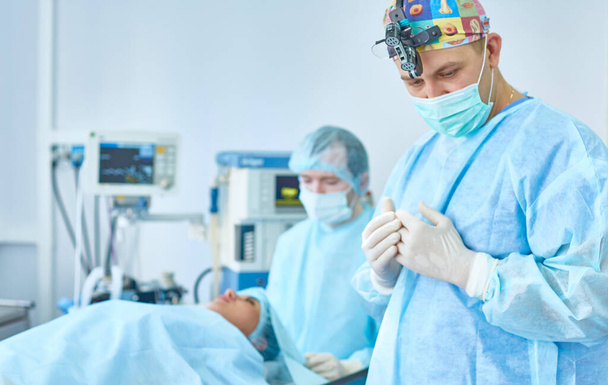 Mehrere Ärzte umgeben Patienten während ihrer Arbeit auf dem Operationstisch. Teamchirurgen bei der Arbeit im Operationssaal - Foto, Bild