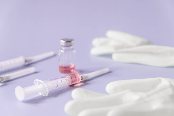 Syringe and ampoule with vitamins or vaccine on a purple background. Treatment concept, soft focus. - Valokuva, kuva