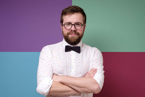 Cute, calm Caucasian bearded man in round glasses with arms crossed. - Photo, Image