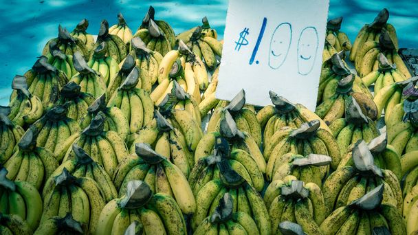 Pile de grappes de bananes mûrissantes naturelles avec étiquette de prix au stand de fruits à Geylang, Singapour
 - Photo, image