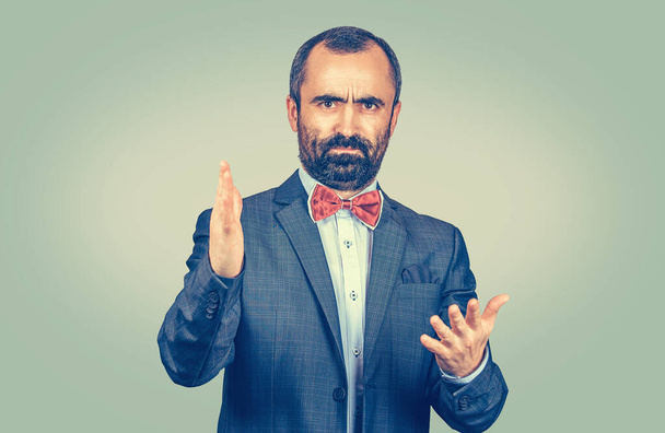 Angry young business man screaming hands in air in frustration looking at you camera mad. Mixed race bearded model isolated on gray background with copy space. Horizontal image - Photo, Image