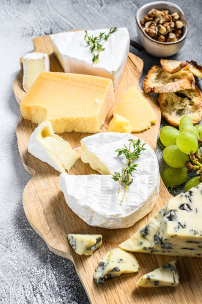 Tabla de quesos con Camembert francés, brie, queso parmesano y azul, uvas y nueces. Fondo blanco. Vista superior. - Foto, imagen