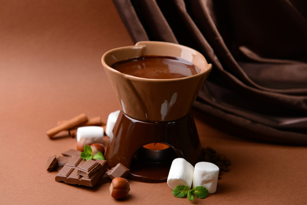 Chocolate fondue with marshmallow candies, on brown background - Foto, imagen