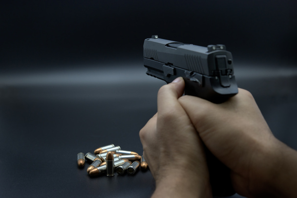 Pistola en mano con munición sobre fondo de hierro oscuro
 - Foto, Imagen