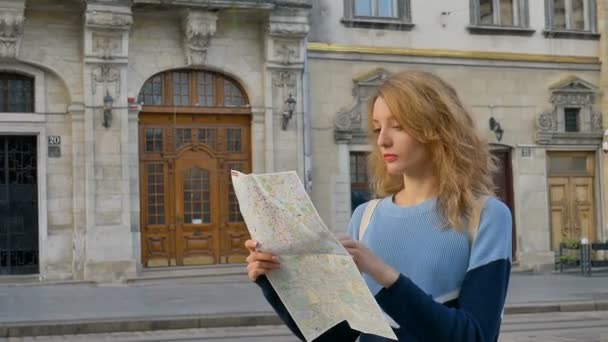 Žena je ztracena ve starém evropském městě, dívá se na mapu a hledá směr brzy ráno na starověkém náměstí. - Záběry, video
