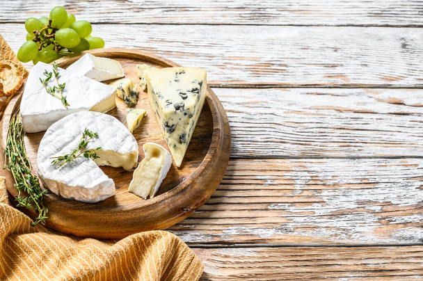 Cheese plate with Camembert, brie and blue cheese with grapes. White wooden background. Top view. Copy space. - Photo, Image