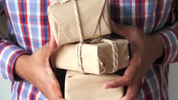 Nahaufnahme eines Mannes, der viele selbstgebastelte Geschenkkartons bei sich trägt  - Filmmaterial, Video