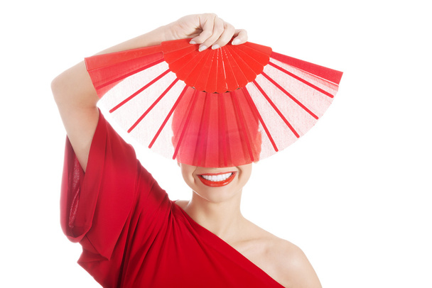 Beautiful woman in red sexy dress with fan. - Foto, afbeelding