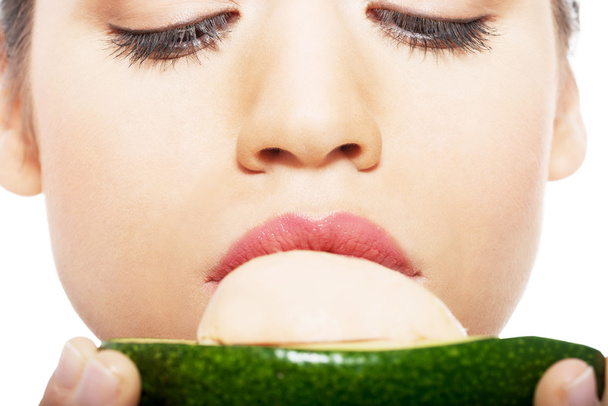 Beautiful woman's face close up and avocado. - Foto, afbeelding