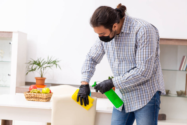 Young male contractor cleaning the house in coronavirus concept - Photo, Image