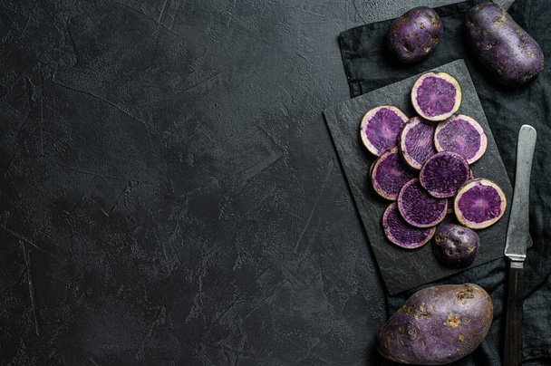 Raw sliced purple potatoes. Black background. Top view. Space for text. - Photo, Image
