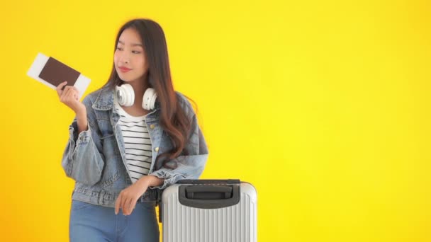 beeldmateriaal van mooie Aziatische vrouw met bagage en vliegticket geïsoleerd op geel - Video