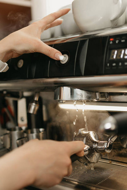 Тесное фото очищения группы с горячей водой в кофеварке в кофейне. Женщина-бариста работает в кафе
. - Фото, изображение