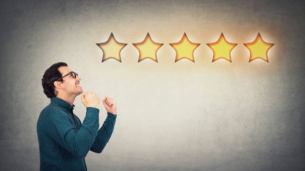 Overjoyed businessman keeps fists tight, celebrate success achievement, as receives positive feedback and approval. Boss, company owner cheerful as earns five stars rating excellent customer service. - Photo, Image