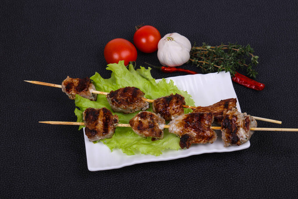 Шашлыки со свиным кебабом в тарелке с листьями салата и помидорами подаются тимьян и чеснок - Фото, изображение