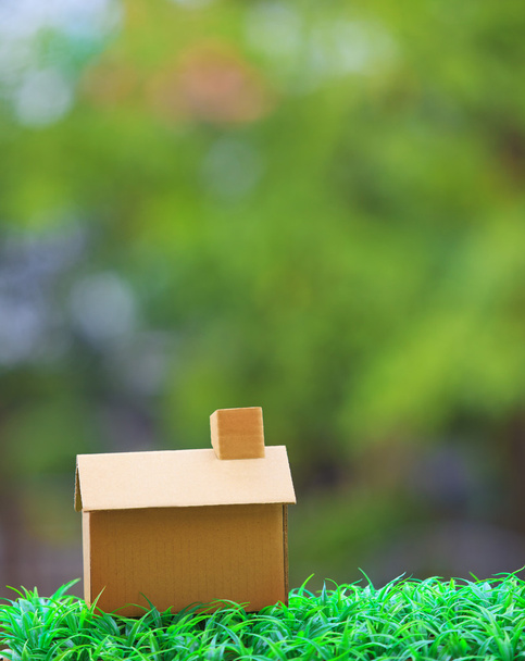 изготовление дома из старой бумажной коробки, лежащей на зеленой траве;
 - Фото, изображение