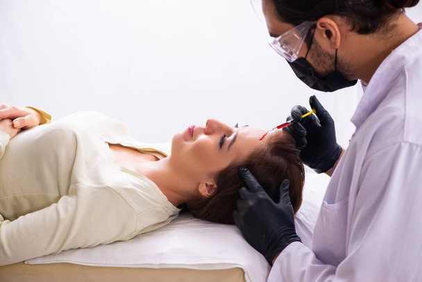 Junge Frau besucht männliche Kosmetikerin bei Haartransplantation - Foto, Bild