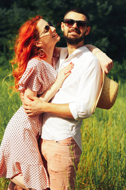 Boldog, szerelmes pár, ölelkezős, vörös hajú lány. Csókolózzunk. dátum attrakció és a szexualitás napszemüveg nyáron - Fotó, kép