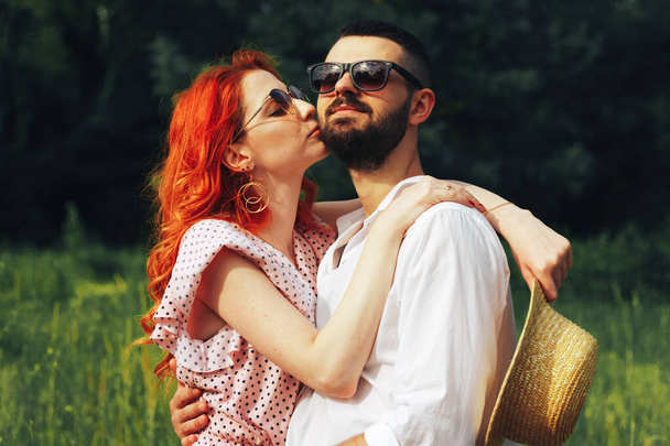Gelukkig, verliefd stel knuffelende, roodharige meid. minuut om te kussen. date attractie en seksualiteit zonnebril in de zomer - Foto, afbeelding