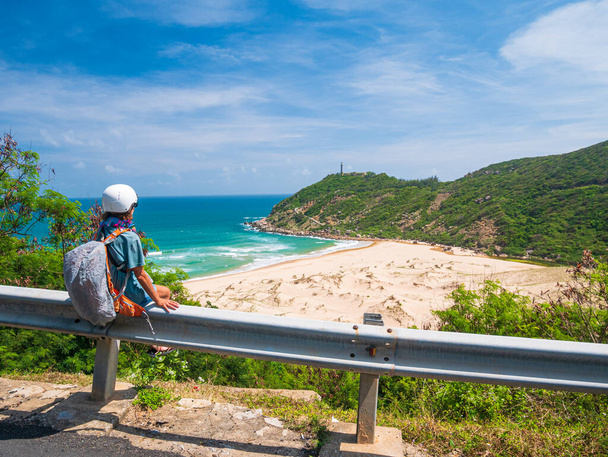 ヘルメットとバイカーは、道路上で休んで、フーイェン省の豪華な海岸の景色を見て、 Nha Trang Quy Nhonは、ベトナムでの冒険。ユニークな熱帯湾と黄金のビーチ. - 写真・画像