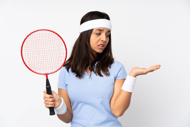 Mladý badminton hráč žena přes izolované bílé pozadí držení copyspace s pochybnostmi - Fotografie, Obrázek