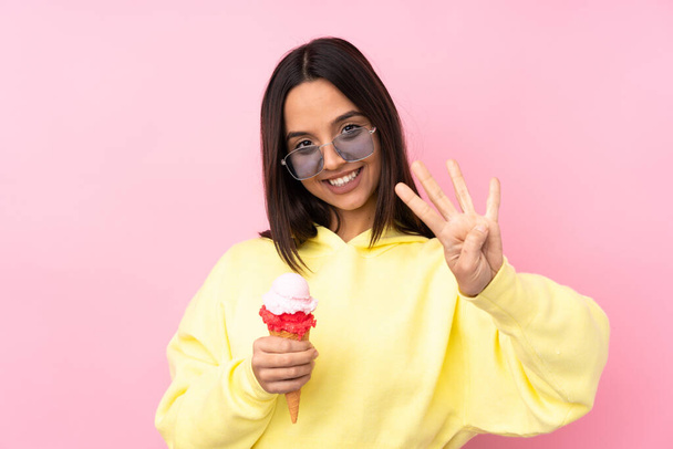 Jeune fille brune tenant une crème glacée cornet sur fond rose isolé heureux et comptant quatre avec des doigts
 - Photo, image