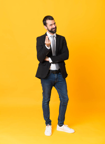 Full-length shot of business man over isolated yellow background making money gesture - Fotoğraf, Görsel