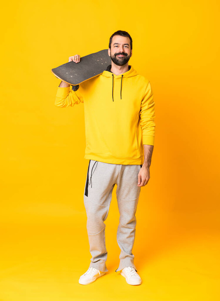 Full-length shot of man over isolated yellow background with a skate - Photo, Image