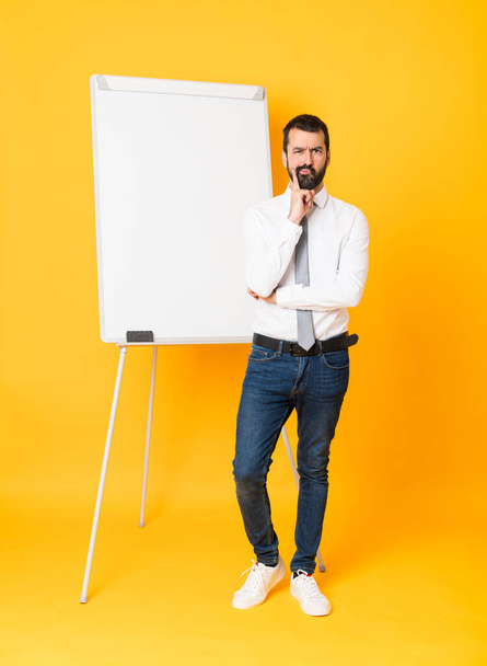 Повнометражний знімок бізнесмена, який дає презентацію на білій дошці над ізольованим жовтим тлом Дивлячись спереду
 - Фото, зображення