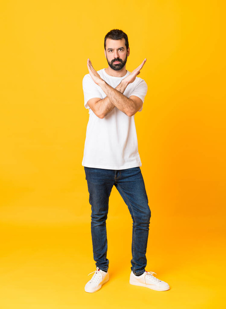 Full-length snímek muže s vousem přes izolované žluté pozadí dělat NE gesto - Fotografie, Obrázek