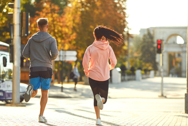 A man and a woman are running along the city street in the morning. - Photo, Image