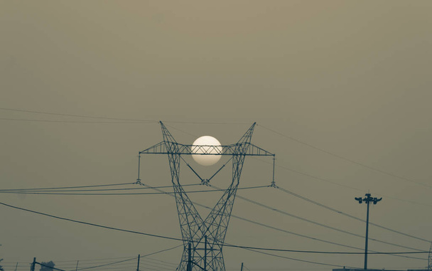 Vintage efekt strzał zachodzącego słońca za wieżami elektrycznymi. - Zdjęcie, obraz