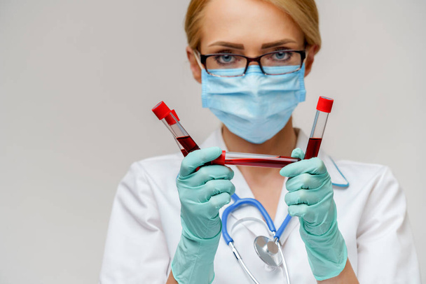 medical doctor nurse woman wearing protective mask and gloves - holding virus blood test tube - Foto, Bild