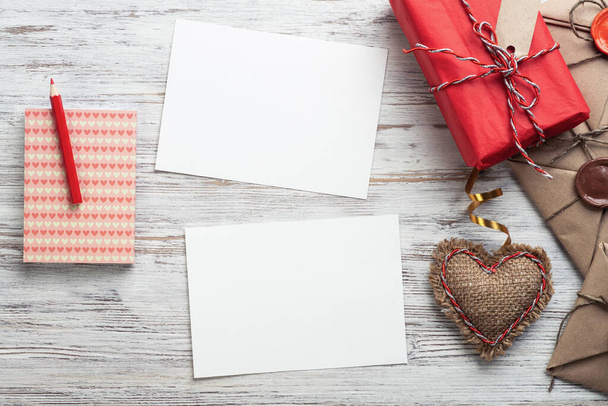 Flat lay cute composition with handmade fabric heart. White paper and retro mail envelopes on wooden table. Happy birthday or anniversary congratulation. Romantic message template with copy space - Φωτογραφία, εικόνα